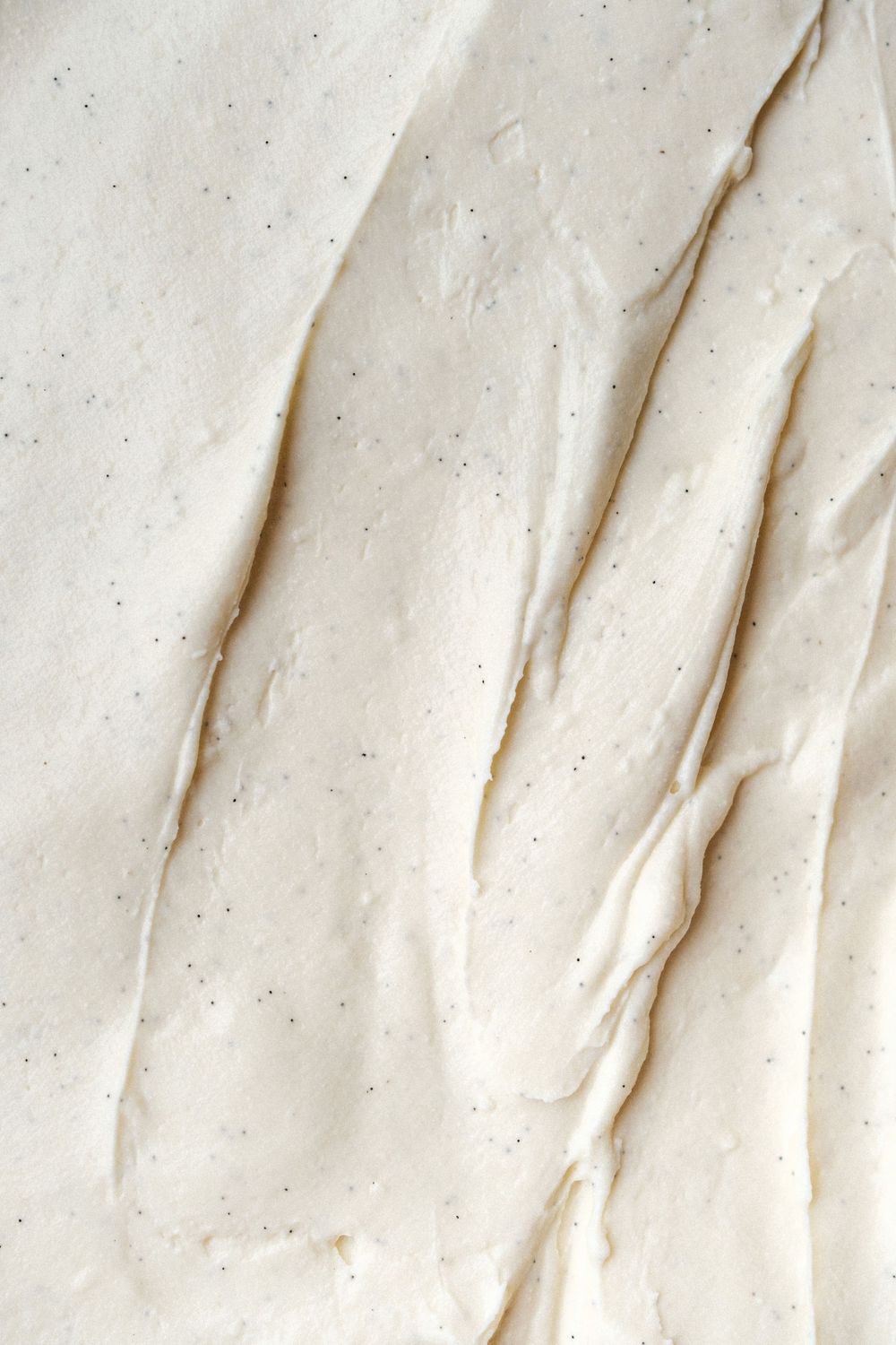 Smooth white vanilla cream texture with subtle ripples and specks.