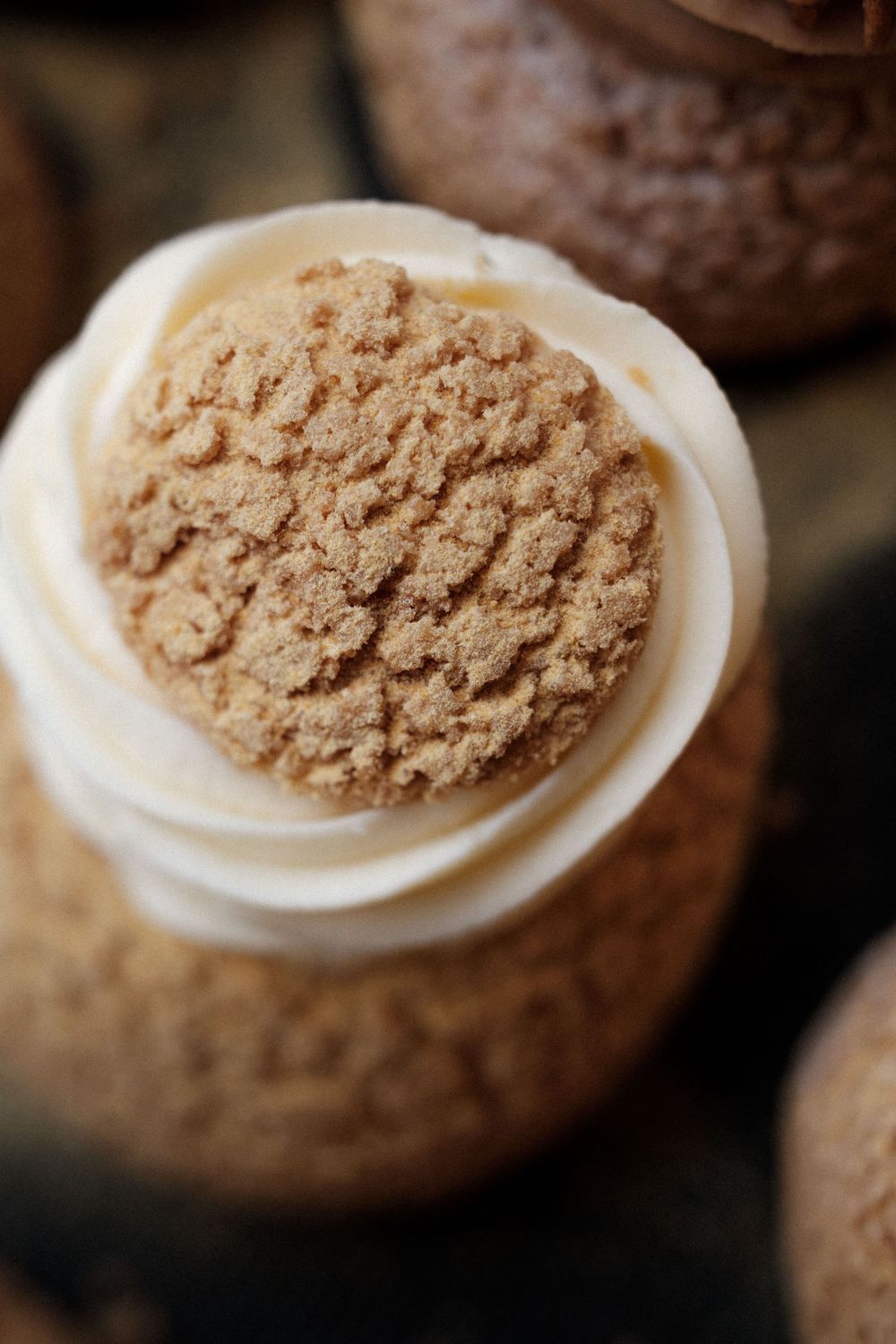 Close-up of a cookie with powdered cocoa topping on white frosting.