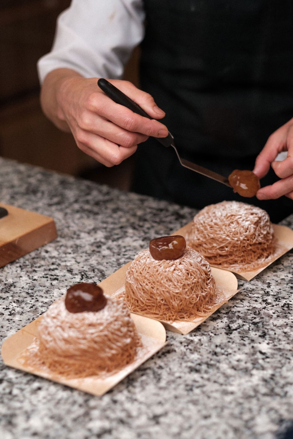 Chocolate desserts with textured toppings being plated on parchment paper squares.