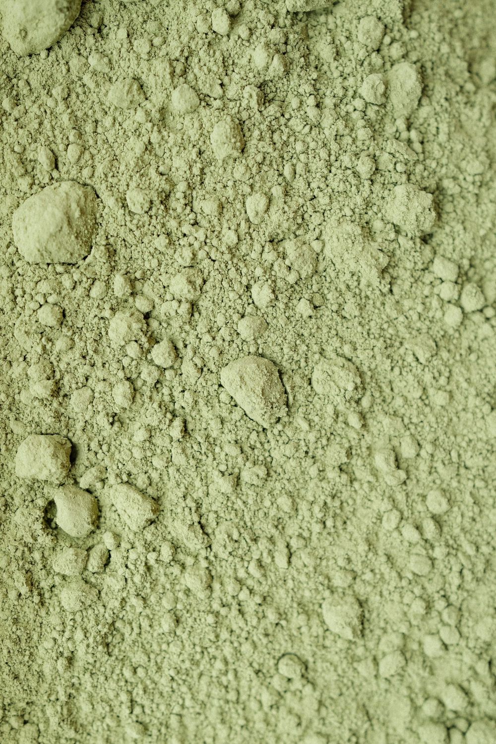 Close-up texture of fine green matcha powder with visible granules.