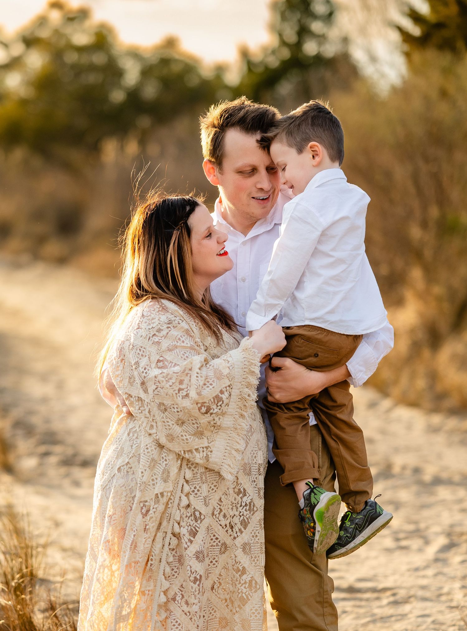 A gentle family moment together outdoors during golden hour in a natural setting with warm sunlight filtering through trees.