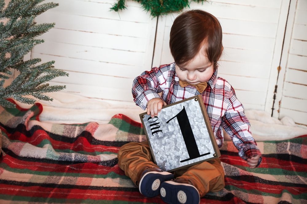 Plaid shirt and brown pants outfit against holiday backdrop with number one sign.