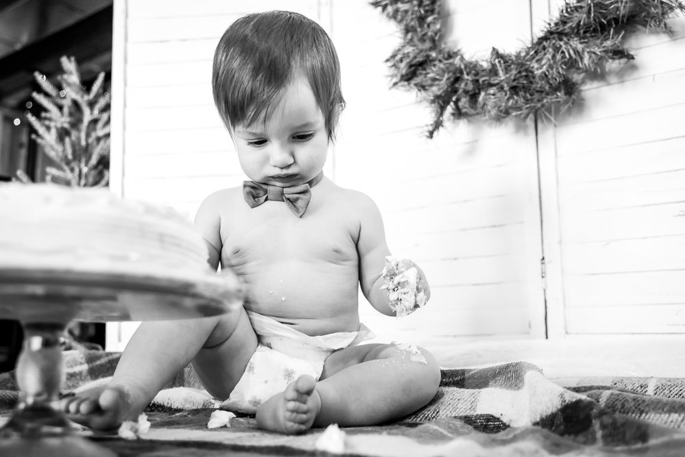 Black and white photo of small child with cake during holiday photoshoot.