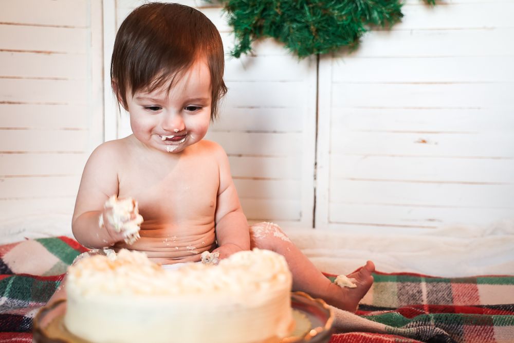 Sweet moment during cake smash photoshoot with frosted cake and holiday decorations.