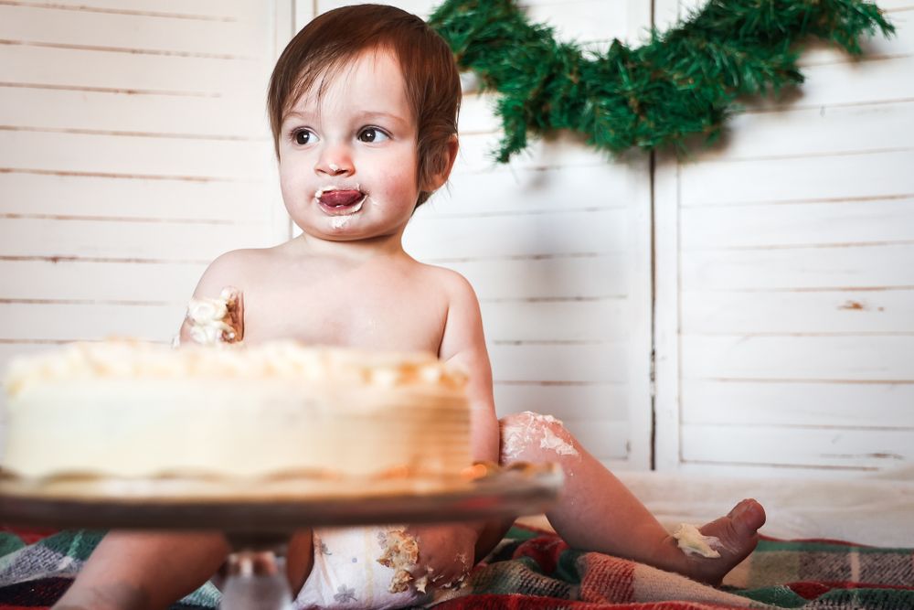 Messy cake smash photography session with holiday decor and white shiplap background.