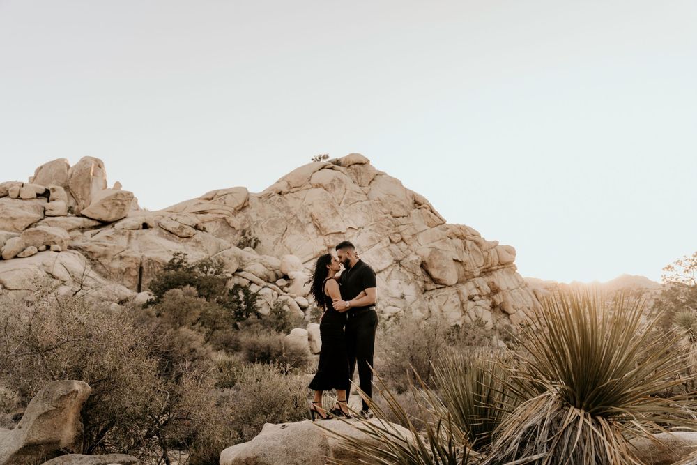 Black and white photo showing a romantic desert scene with towering rock formations and desert plants.