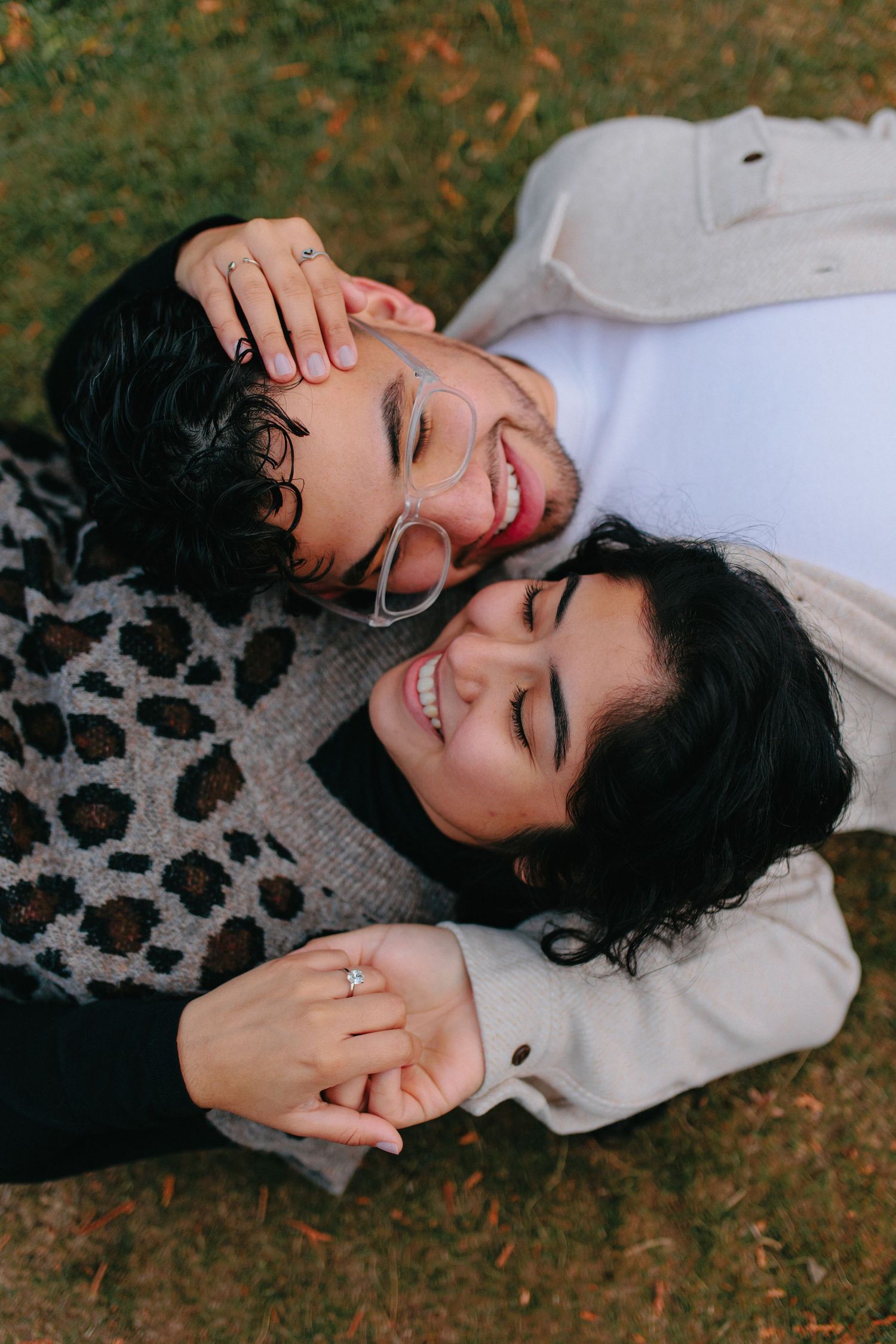 Two people lying down together sharing intimate moments during an autumn photoshoot.