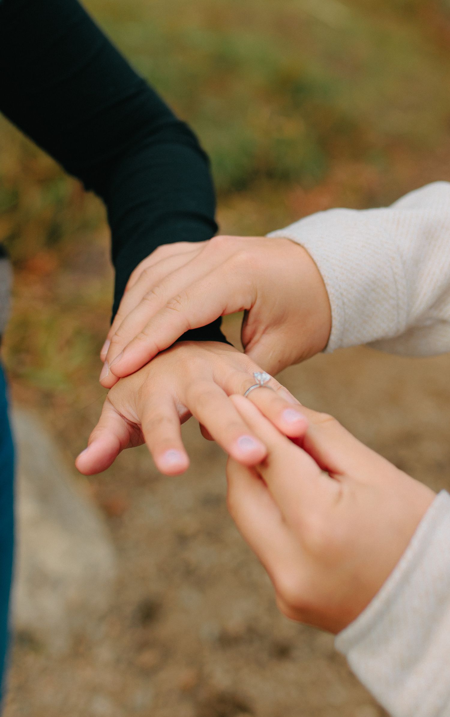 Close-up series of hands holding and exchanging a delicate ring in a romantic outdoor setting.