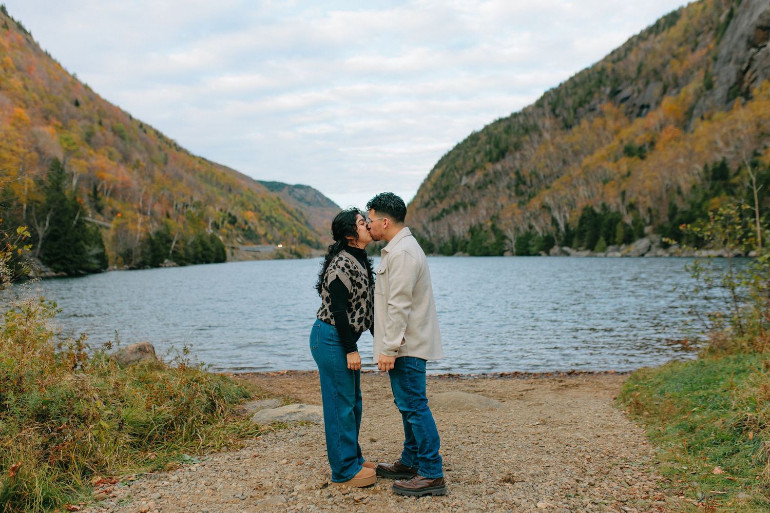 A scenic view of Acadia National Park's Jordan Pond with autumn foliage reflecting in the calm waters.