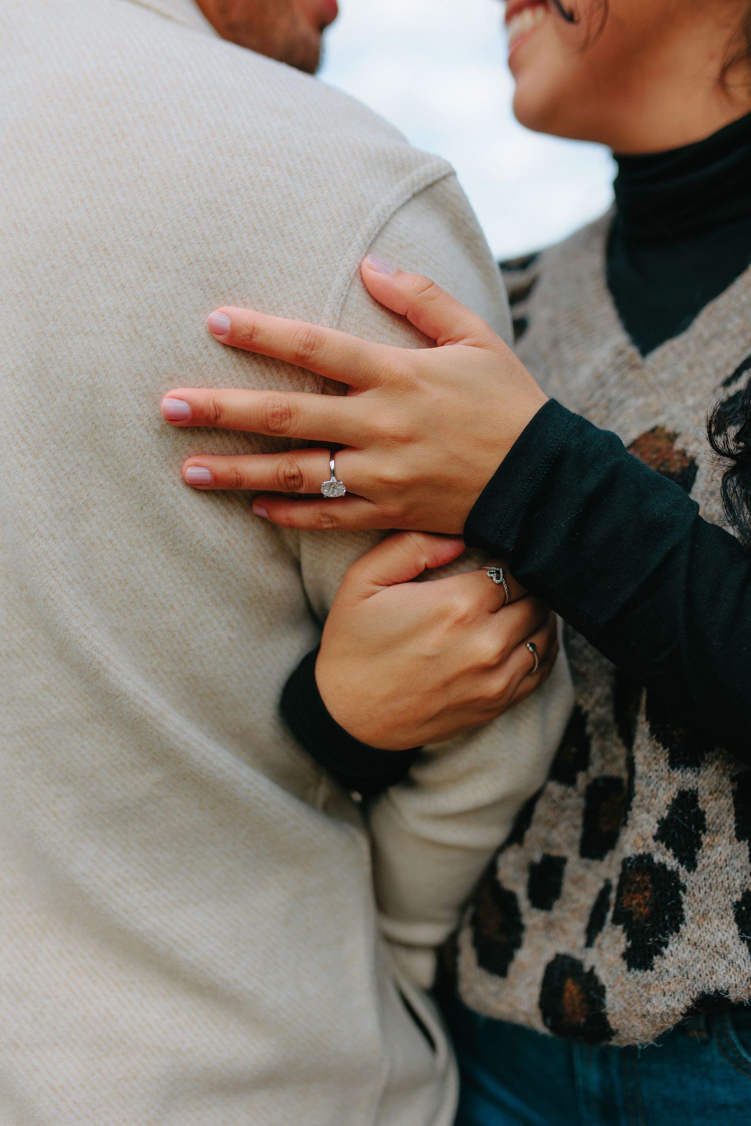 Close-up shots of hands wearing a leopard print sweater and beige sweatshirt during an intimate moment.
