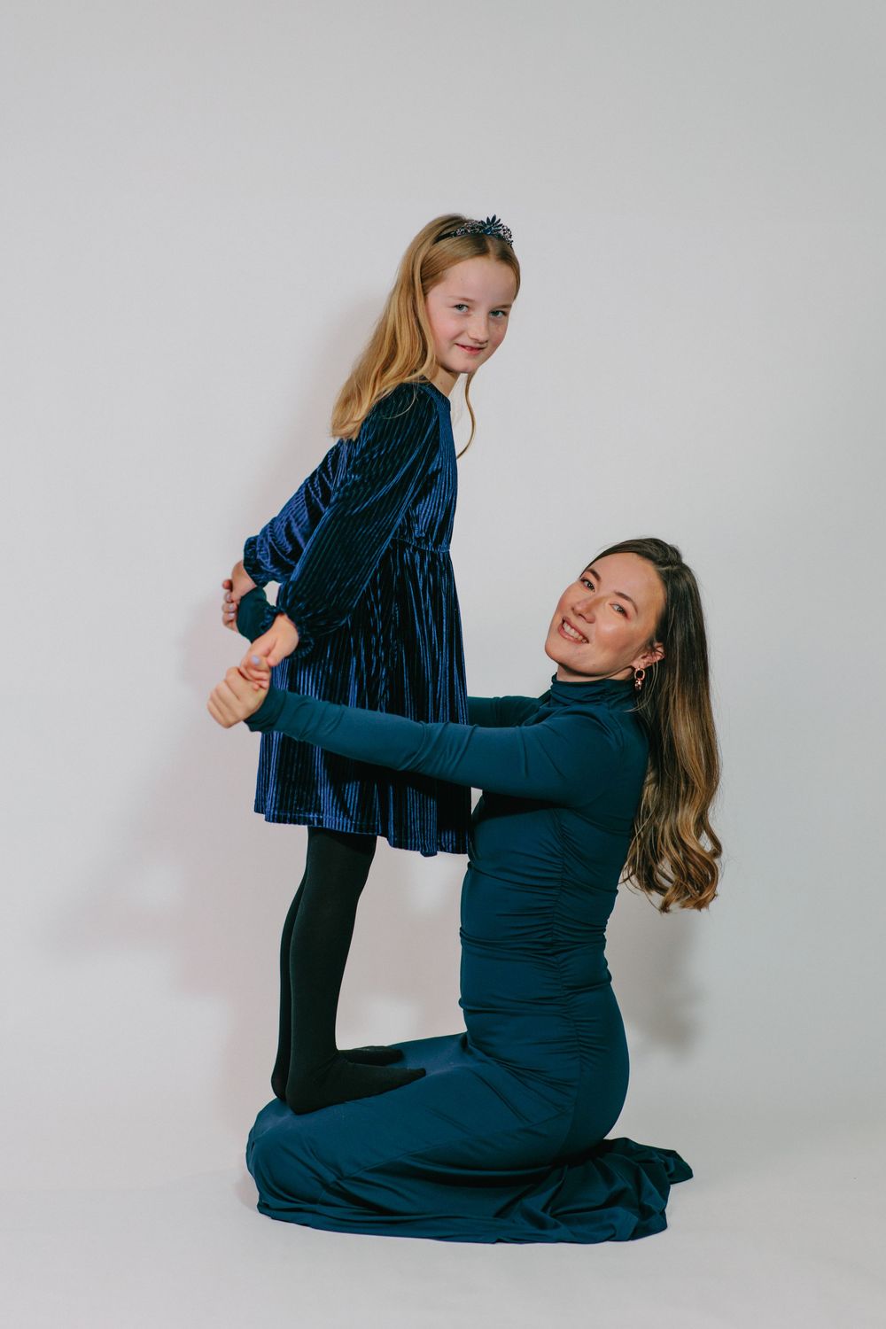 Two dancers in dark blue outfits perform a graceful contemporary dance sequence against a light background.