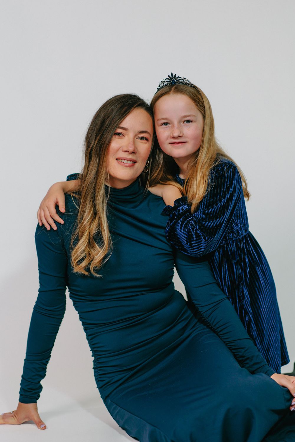 Two people wearing navy blue outfits pose together in a series of casual studio portraits against a light background.