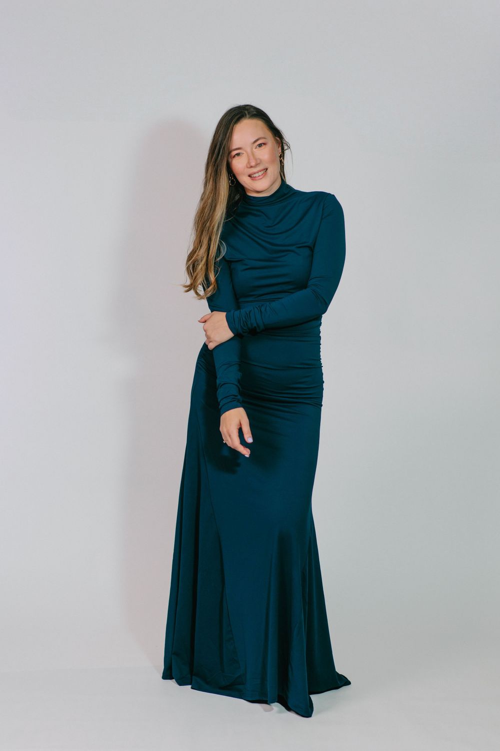 Woman in navy long-sleeved dress poses in multiple shots showing different angles and movements against light background.