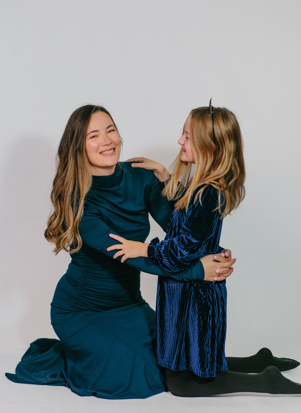 Two people in dark blue outfits sit together on a white background in a series of candid interaction shots.