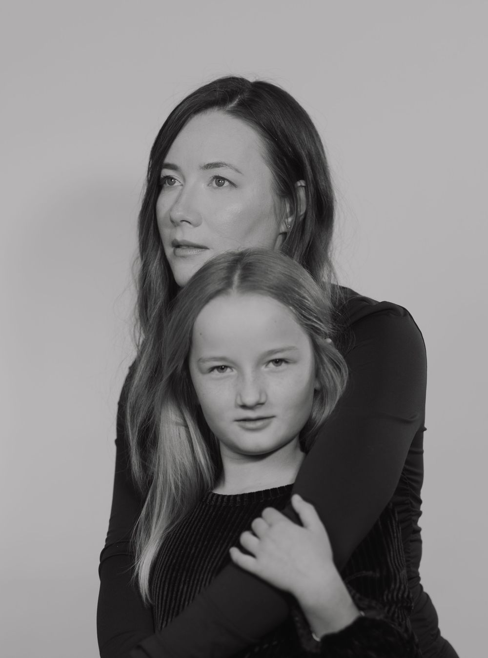 Black and white artistic portrait series showing a person in dark clothing against a light background posing in different angles.