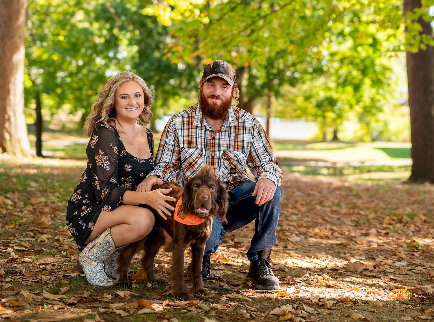 Couple relaxing together on fallen autumn leaves in a sunlit park setting.
