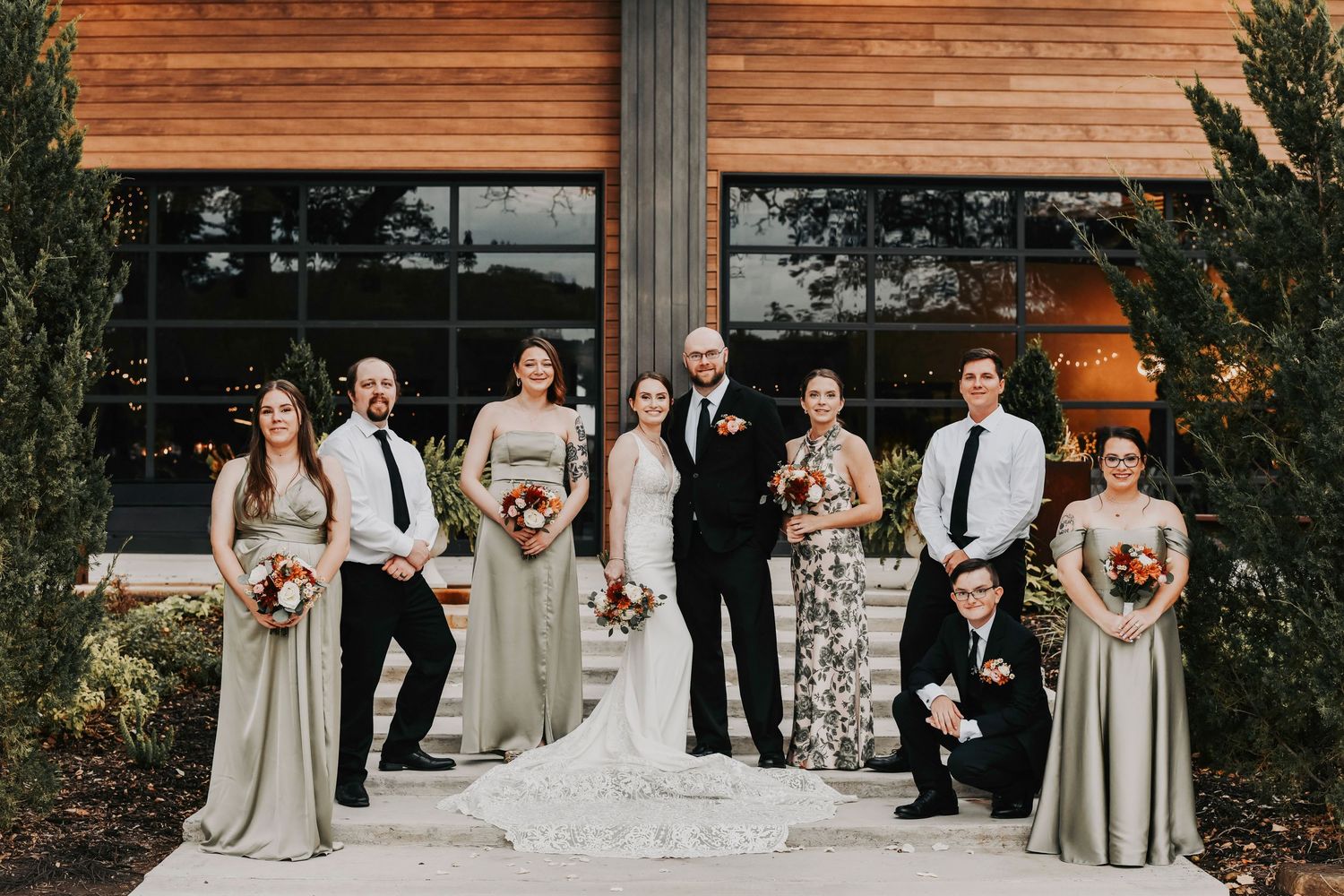 a wedding party in a sea green and botanical color palette pose for their wedding photos in weatherford