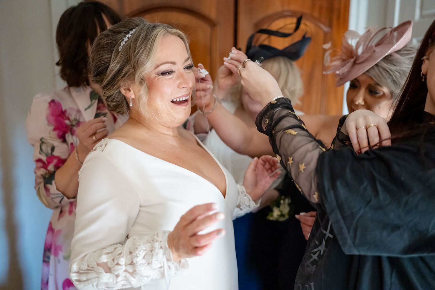 A joyful moment during wedding preparations as finishing touches are applied to the bride's look.
