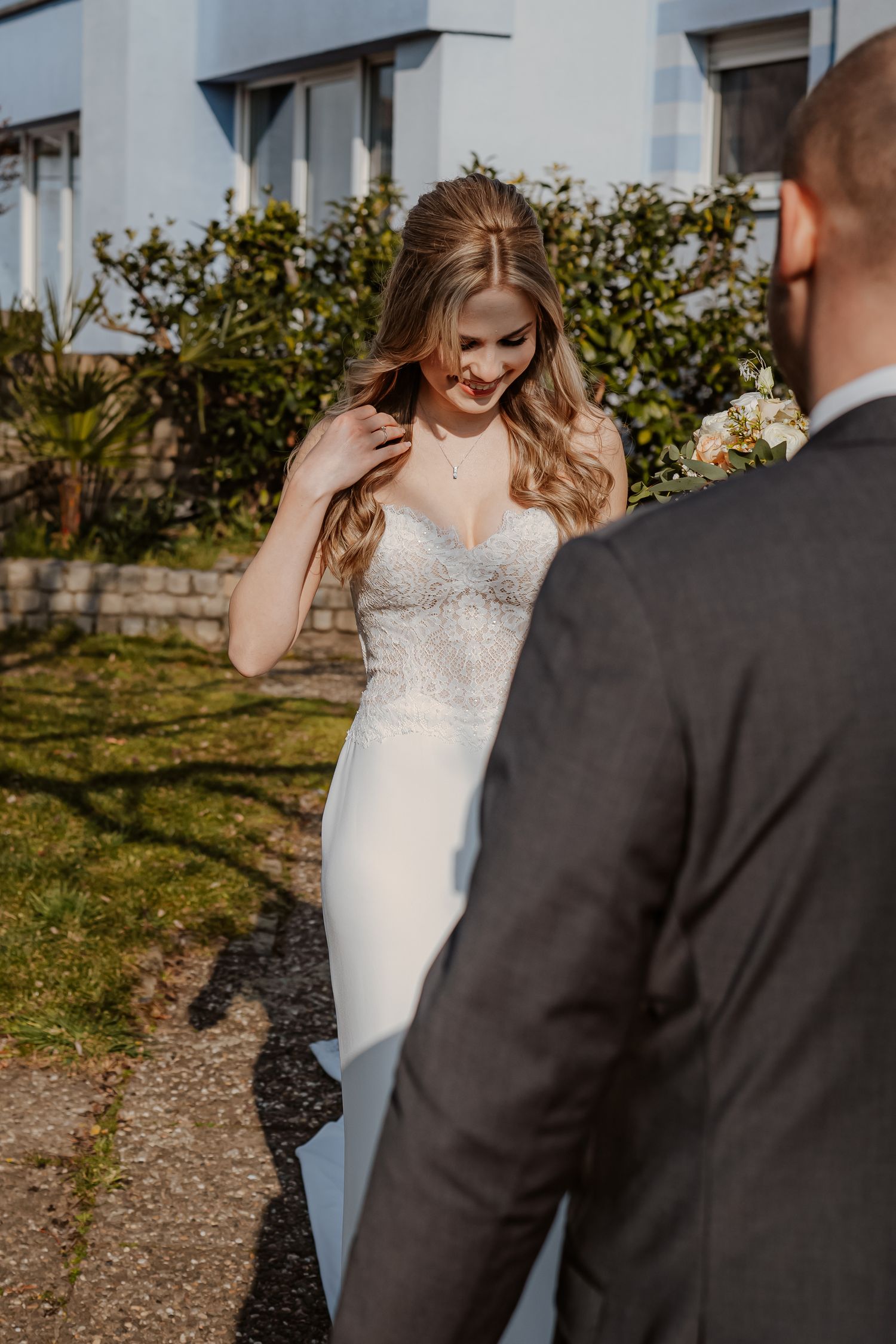 A romantic couple in white clothing shares an intimate moment in a wooded setting during golden hour.