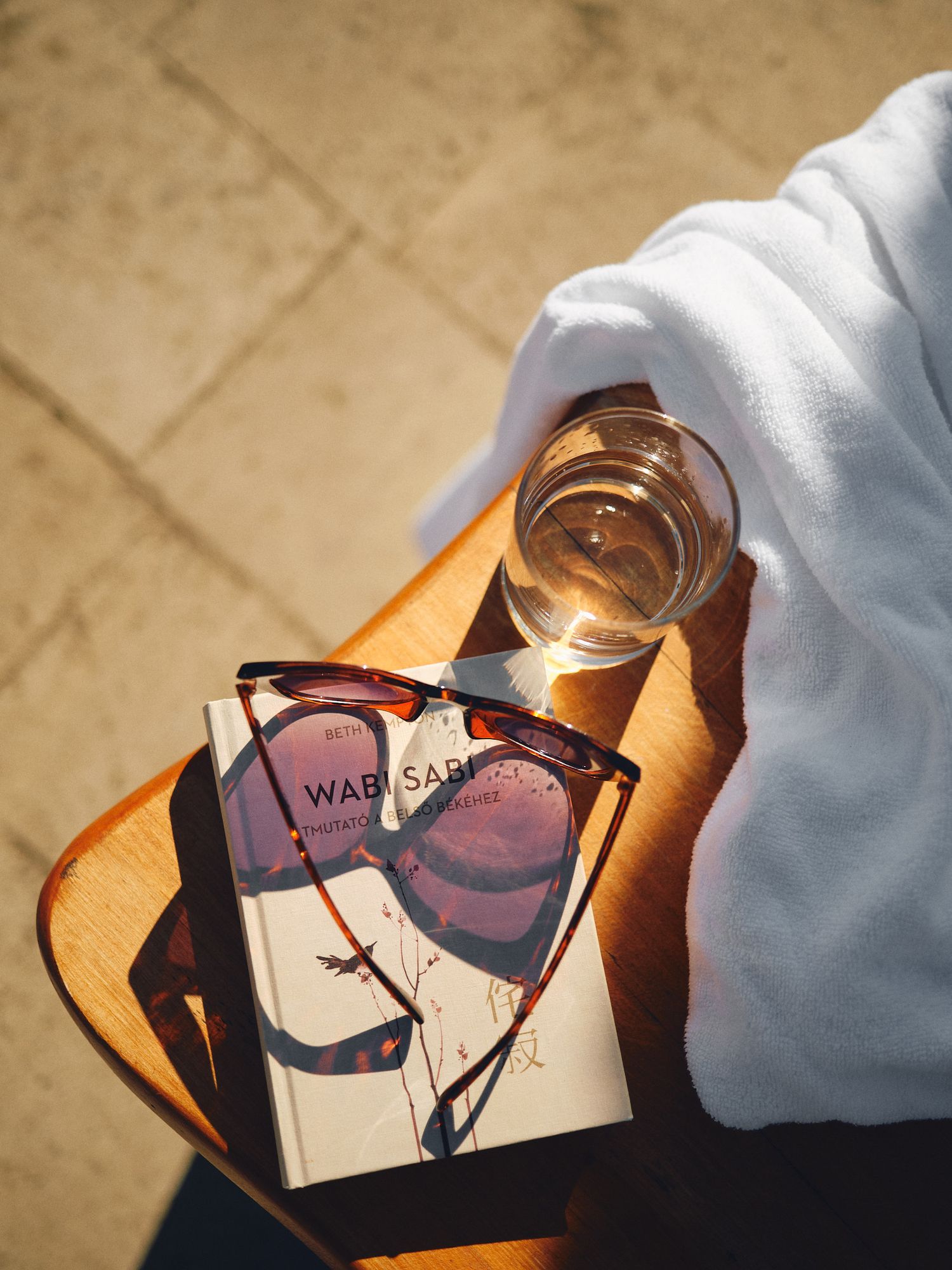 A pair of brown sunglasses with tinted lenses casting shadows on a light-colored surface in natural lighting.