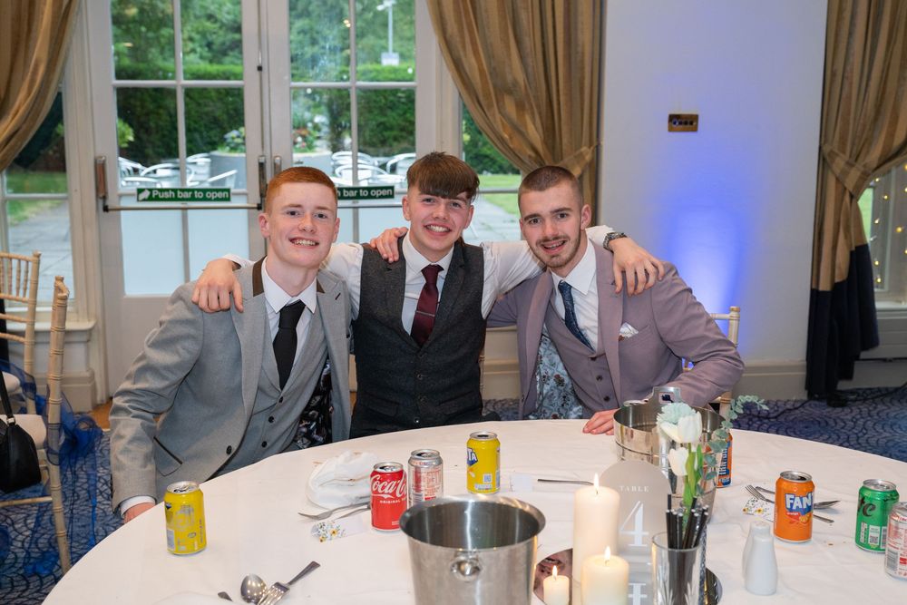 Young people in formal attire gathered around tables at a celebratory event.