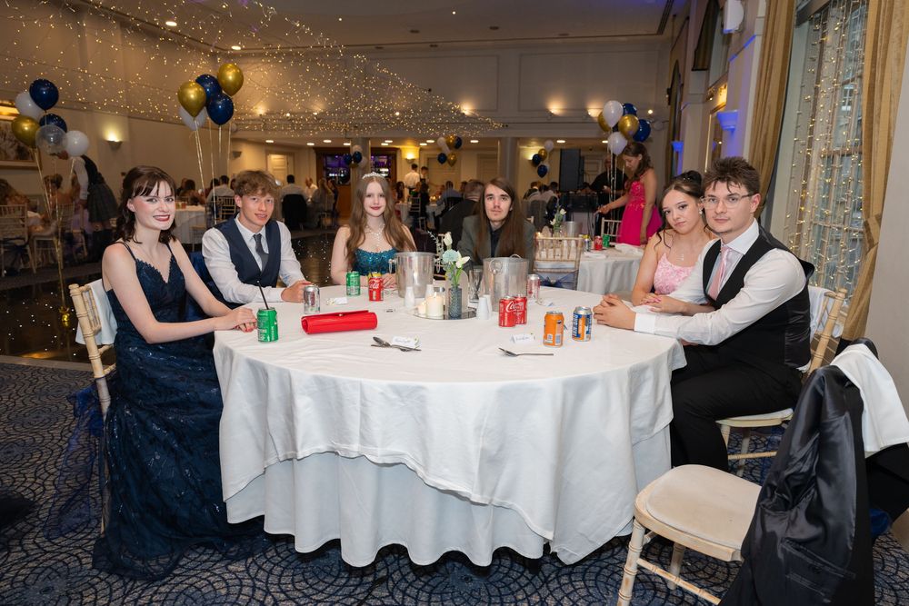 Guests enjoying a formal dinner reception at round tables with white tablecloths and ambient lighting.