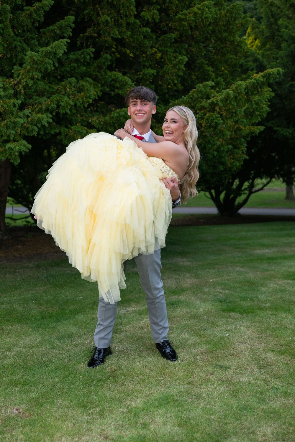 Playful scene on a lawn with flowing yellow formal dress being carried.