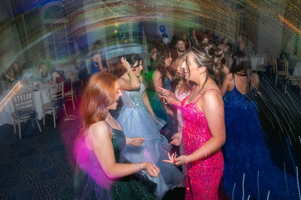 Guests dancing and celebrating on a dimly lit dance floor at an evening event.
