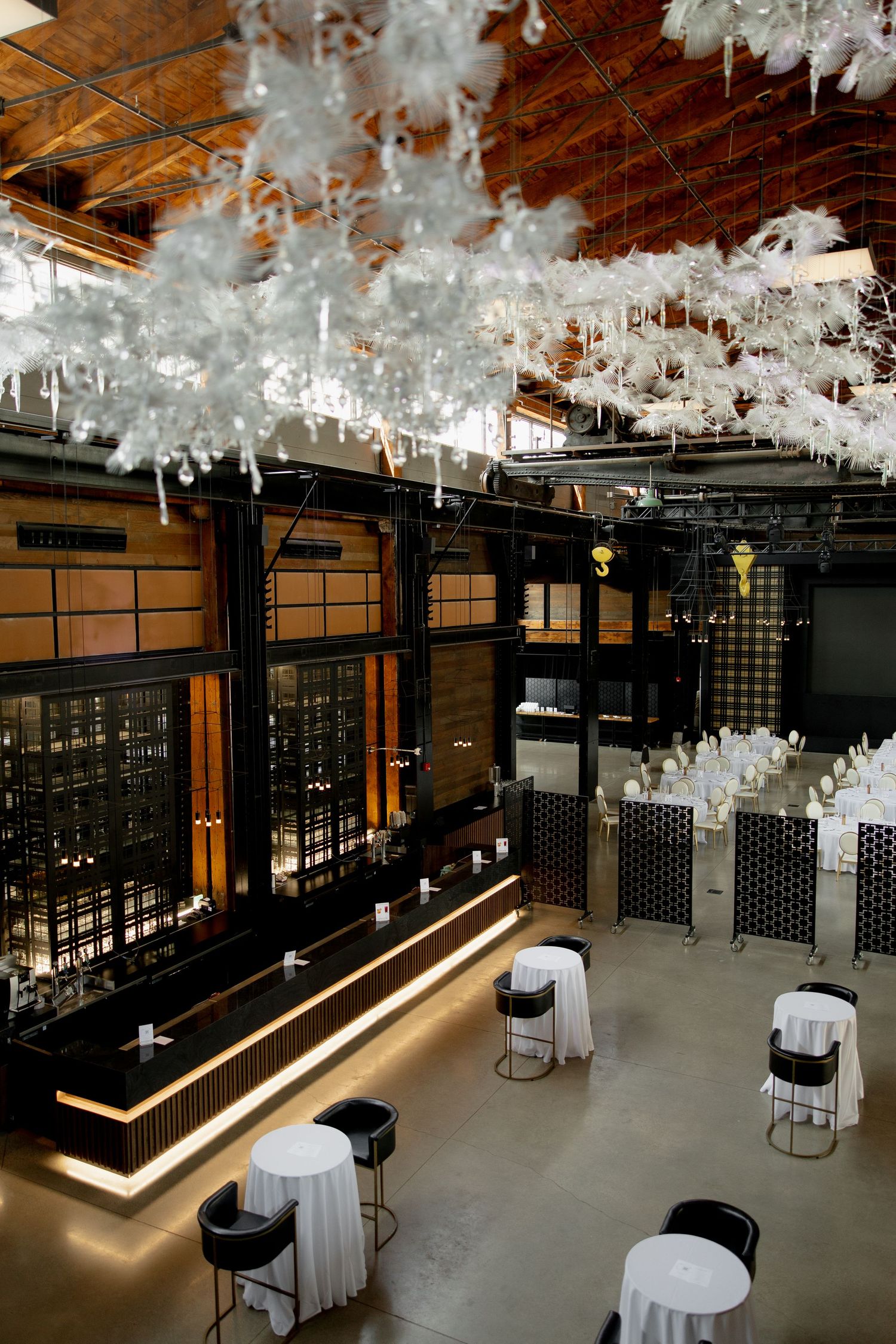Modern event space decorated with suspended white feather installations and ambient lighting.