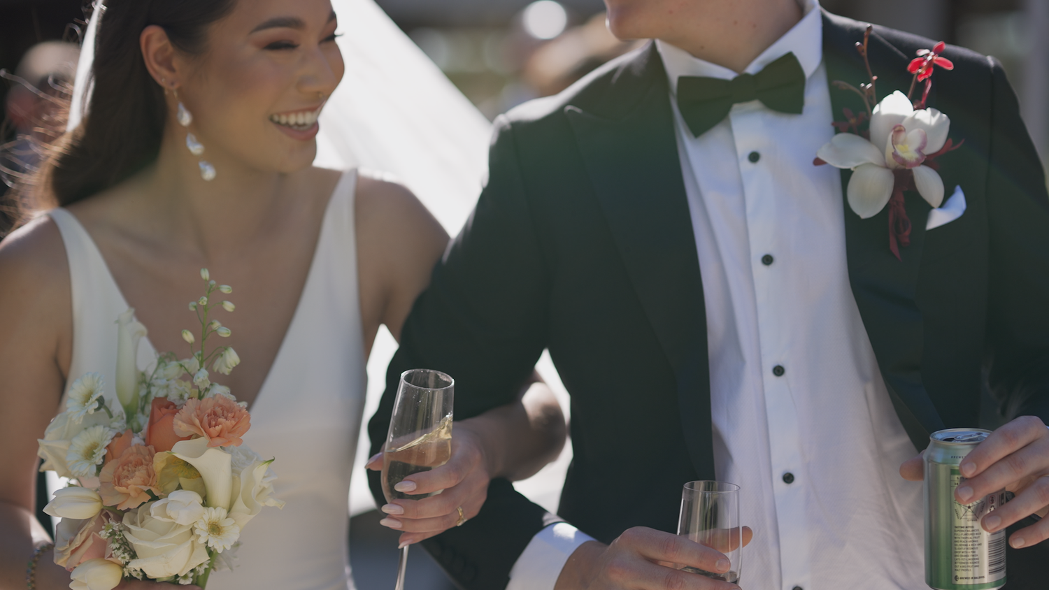Elegant couple in formal wedding attire holding champagne glasses during celebration.