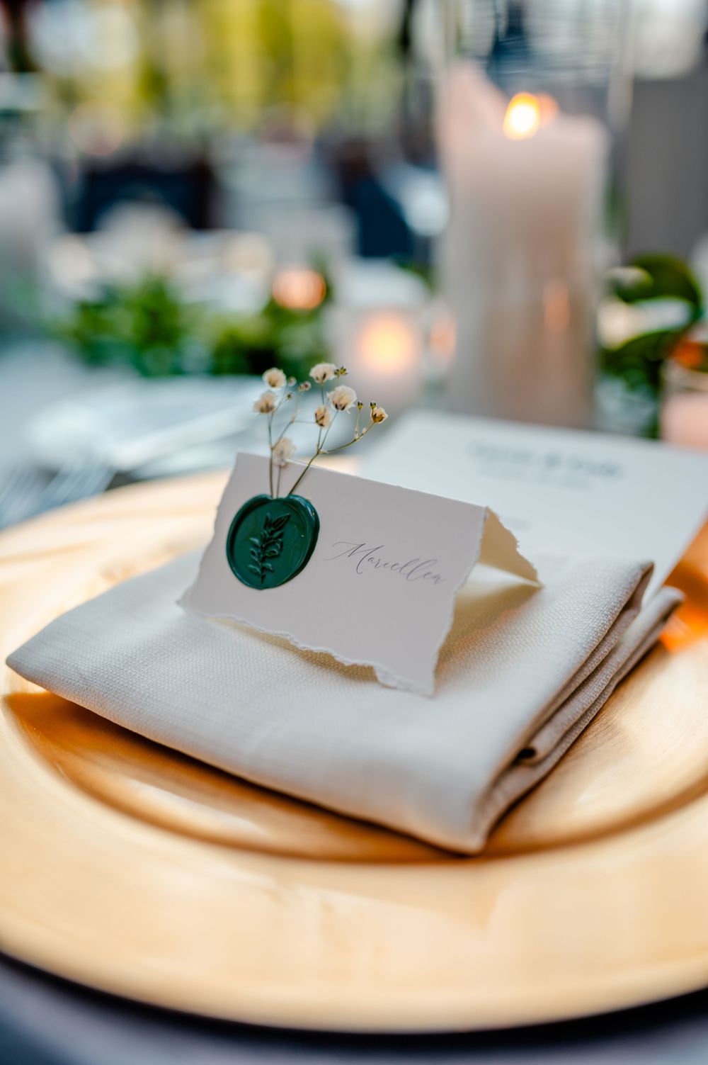 Elegant table setting with white napkins and delicate floral accents on cream colored plates.
