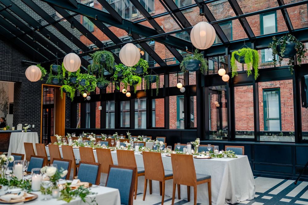 A rustic indoor wedding reception venue with exposed brick walls, paper lanterns, and elegant table settings.