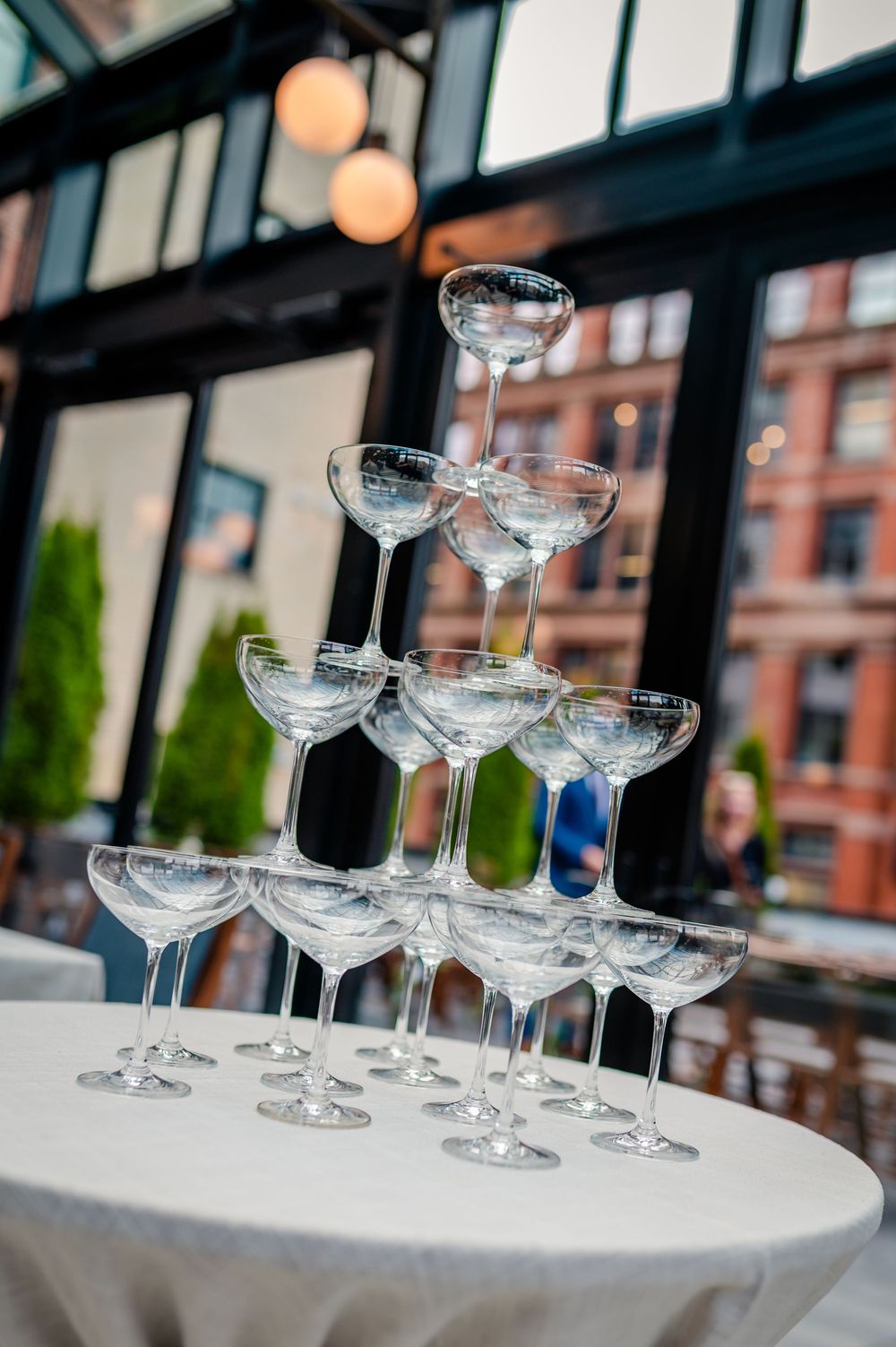 Empty champagne glasses arranged in rows on a white tablecloth at an elegant event setting.