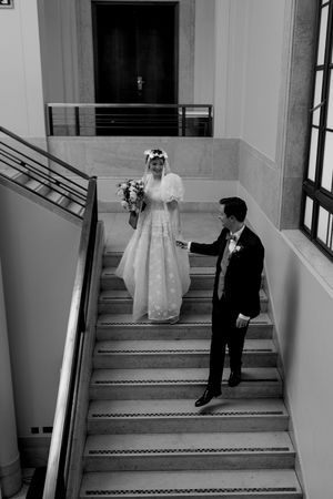 A wedding couple descends a grand staircase in a series of black and white photographs.