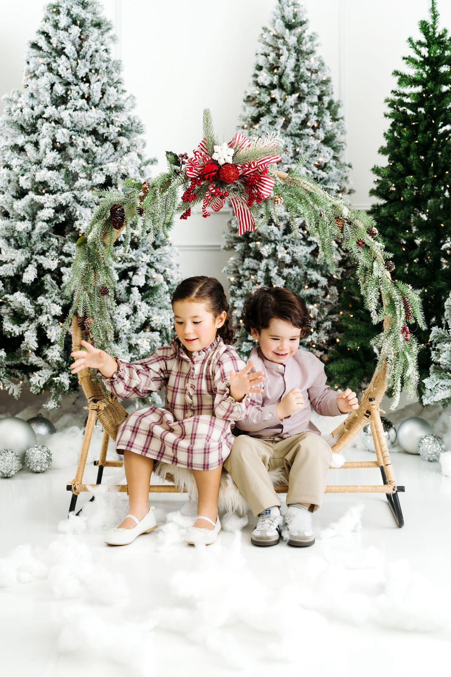 Child sitting inside large Christmas wreath in holiday photoshoot