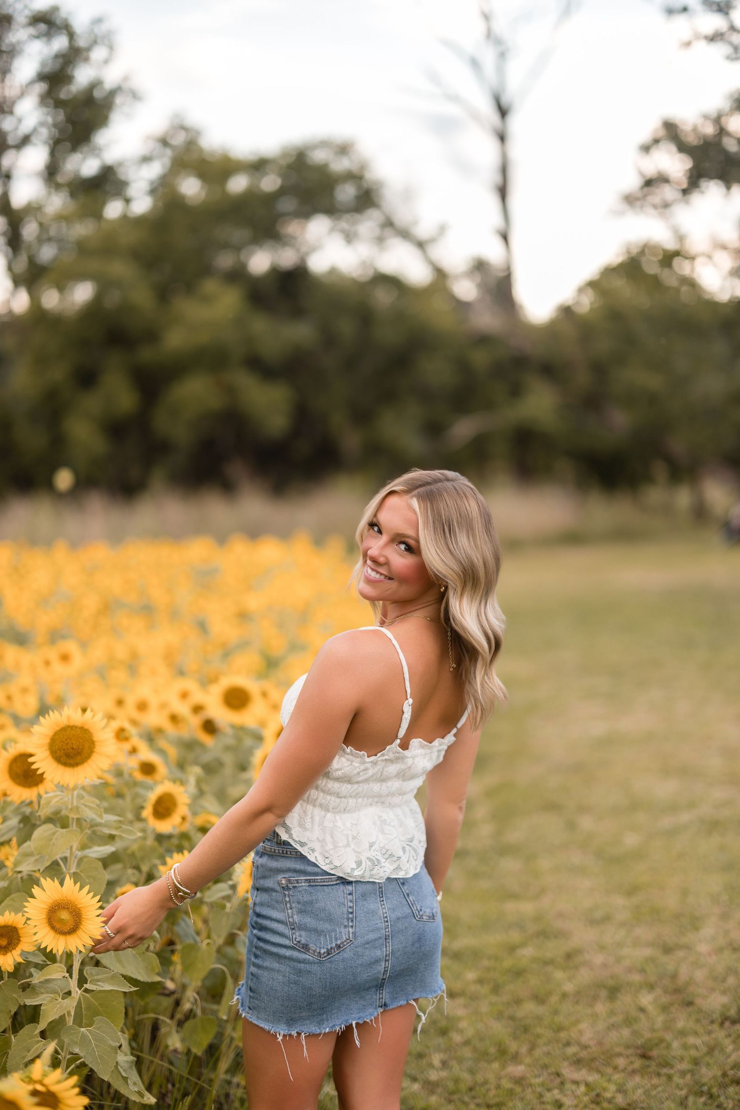 A series of photos showing someone in a white top and denim shorts exploring a vibrant sunflower field at sunset.