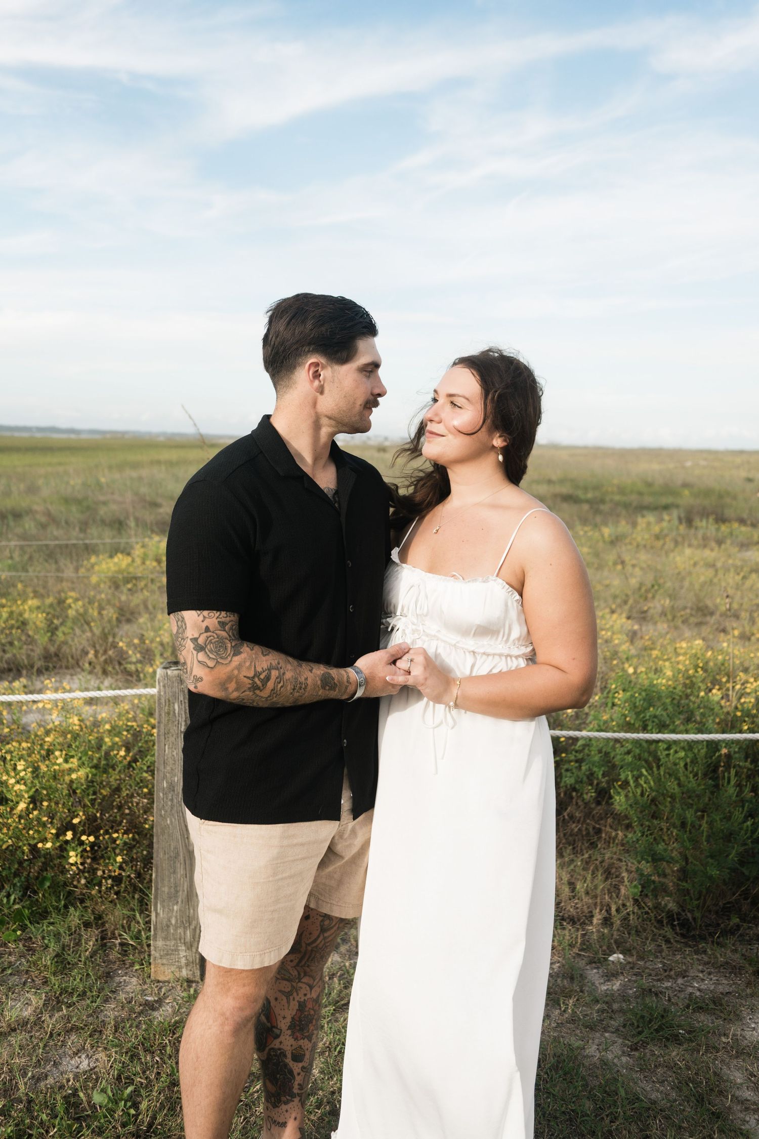 A couple shares romantic moments together in a field of yellow wildflowers at sunset.