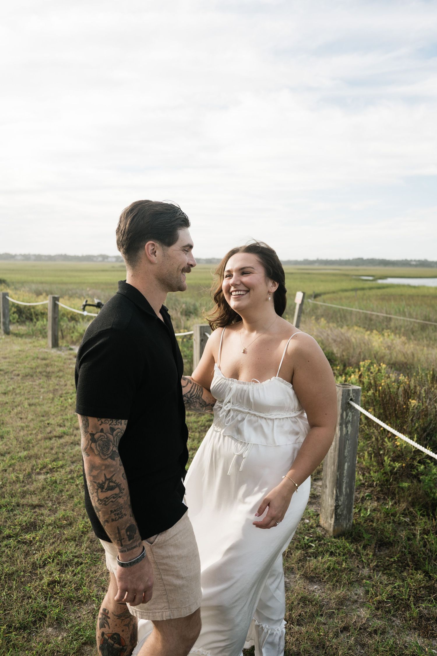 A couple shares intimate moments in a grassy field during an outdoor photo session.