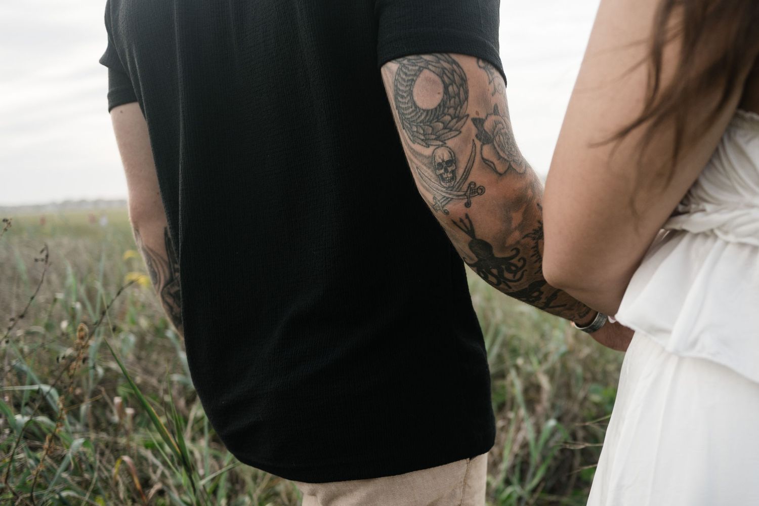 A couple shares a tender moment in a rustic field with tall grass and soft natural lighting.