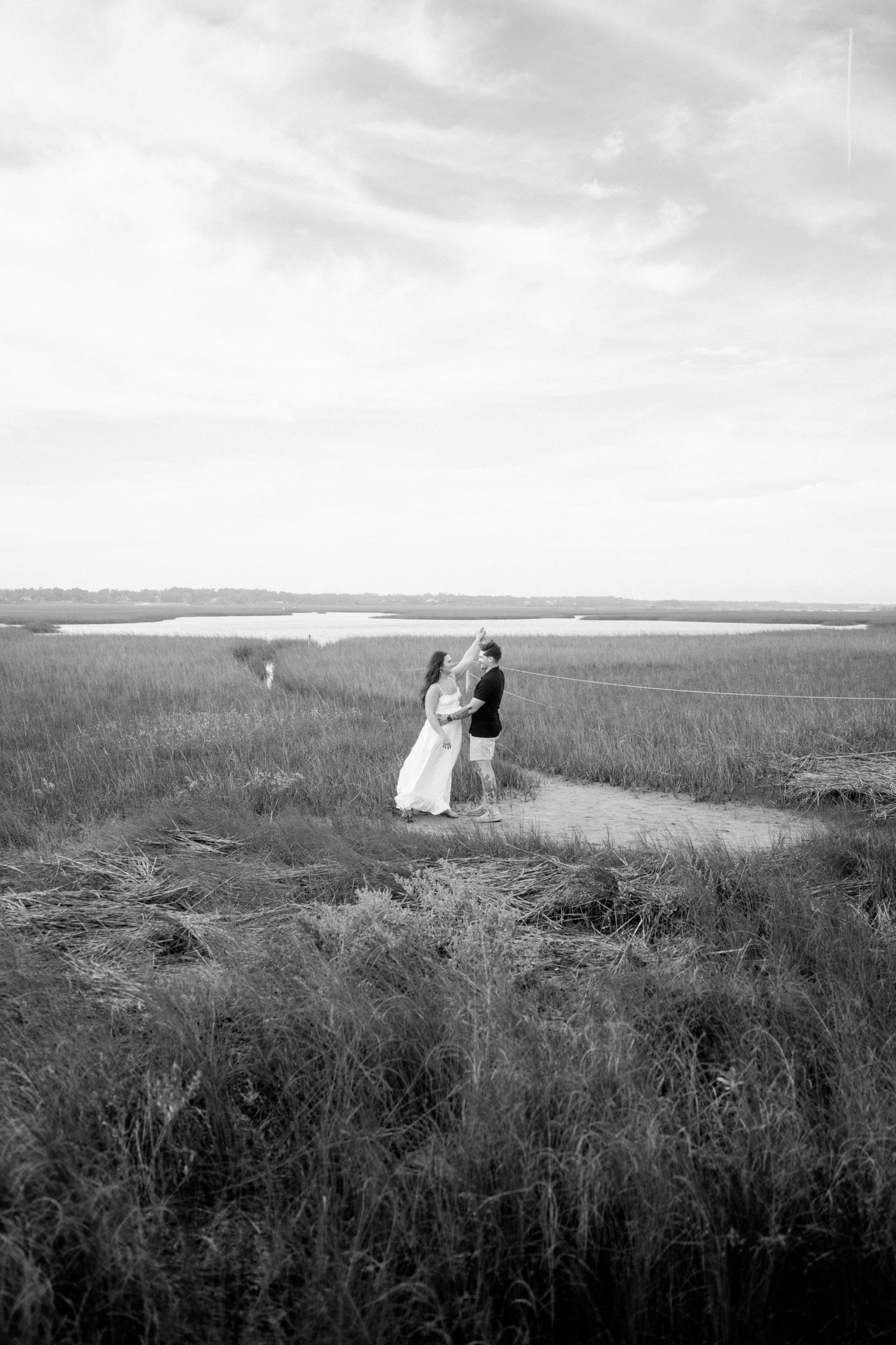 A romantic black and white photo of a couple walking on a scenic coastal trail.