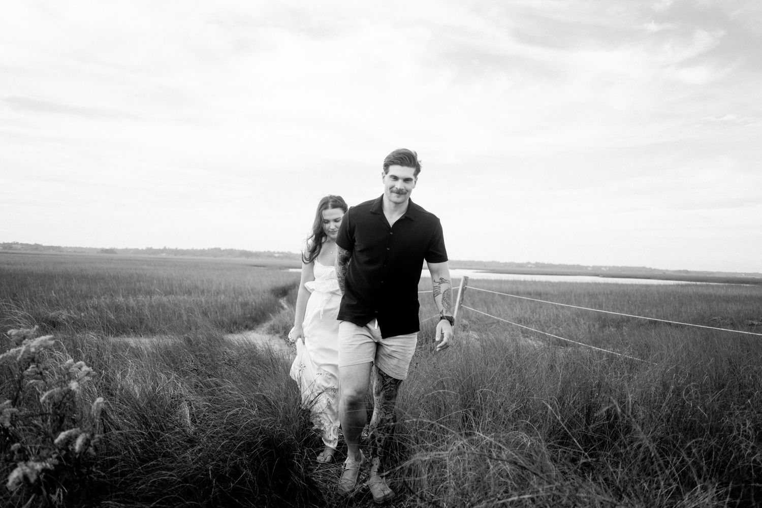 A series of black and white landscape photographs showing people walking through a vast open field.