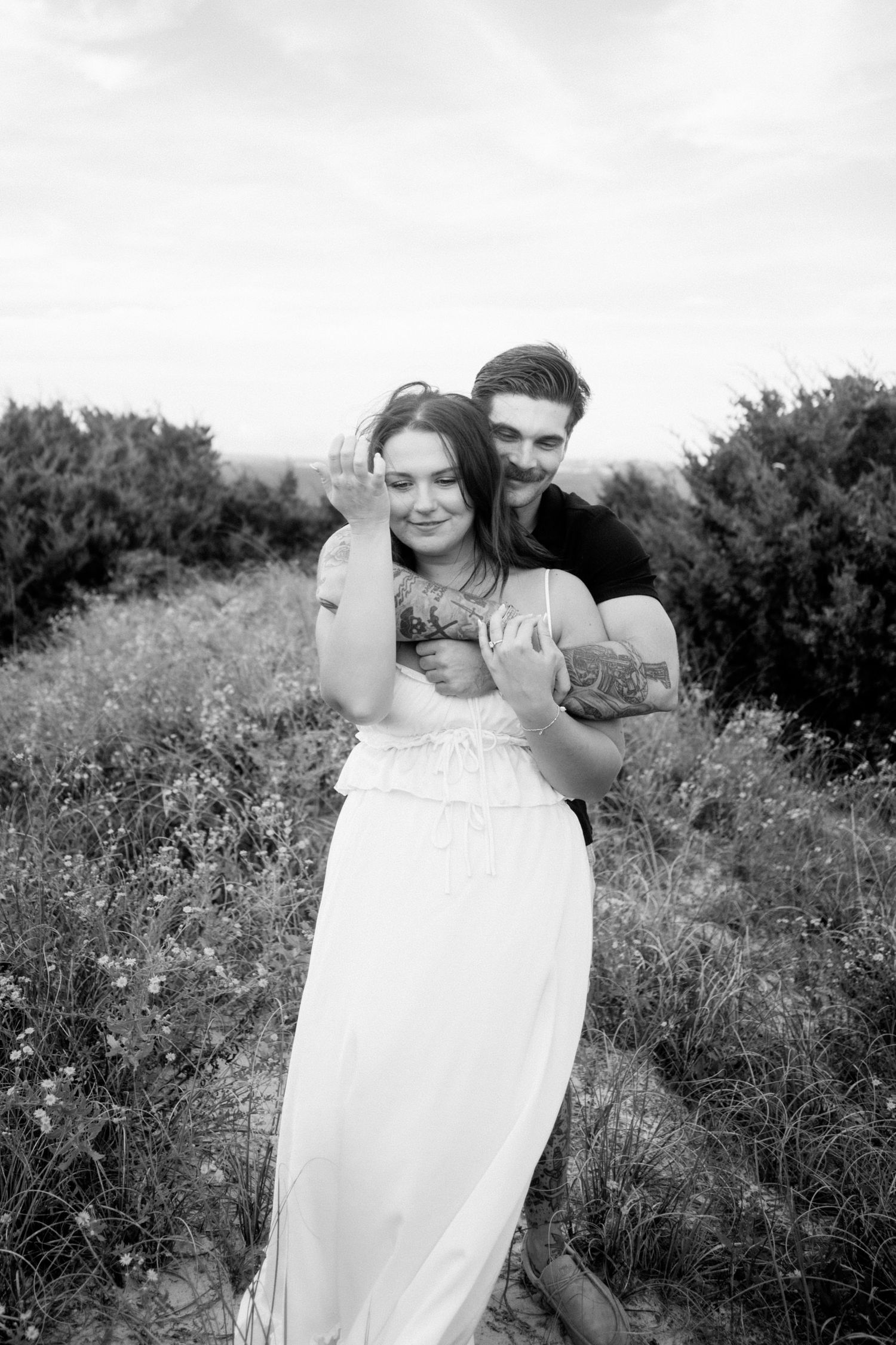 A playful couple poses in a field of wildflowers on a sunny day.