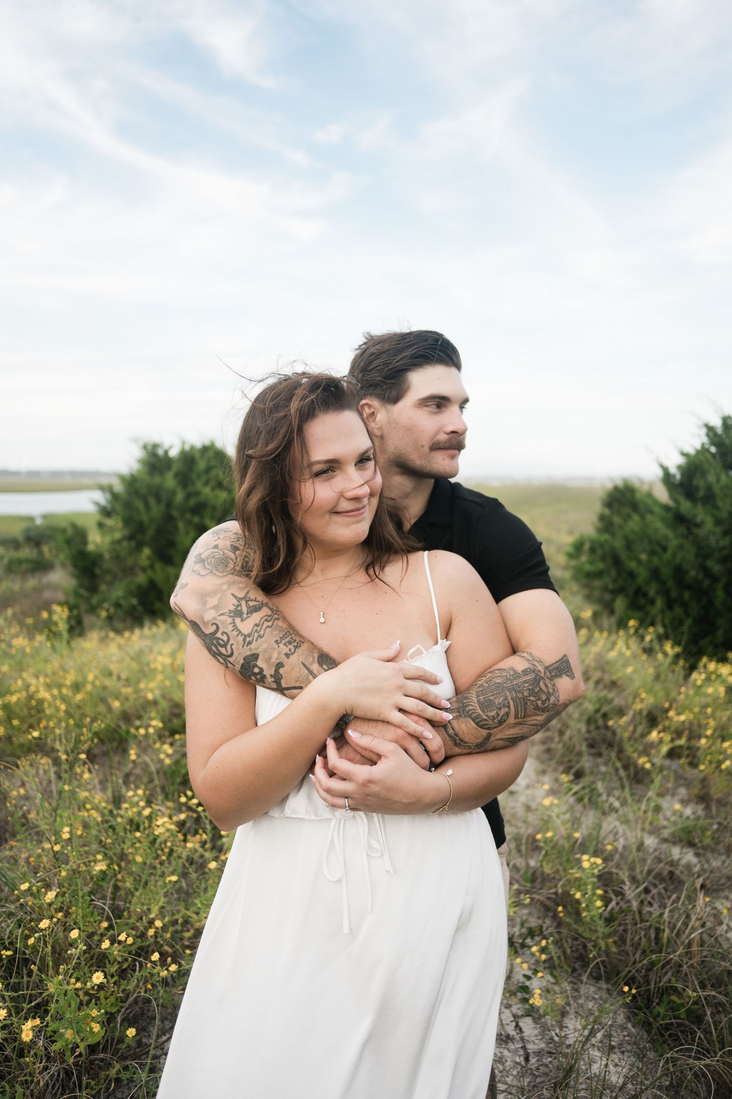 A couple embraces in a field of yellow wildflowers during a romantic outdoor photoshoot.