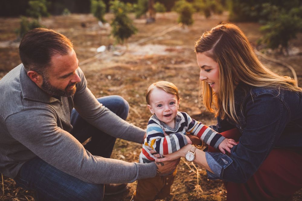 Family enjoying quality time together on a picnic blanket during golden hour in a rustic outdoor setting.