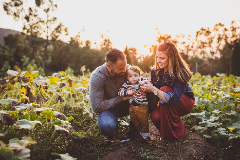Family enjoying a tender moment together in a sunlit garden with blooming flowers at sunset.