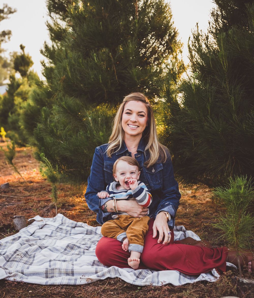 Family portrait session in a pine forest with blanket spread on ground during golden hour sunset.