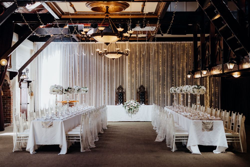 Dramatic wide-angle view of an all-white wedding venue with flowing drapes and elegant table settings.