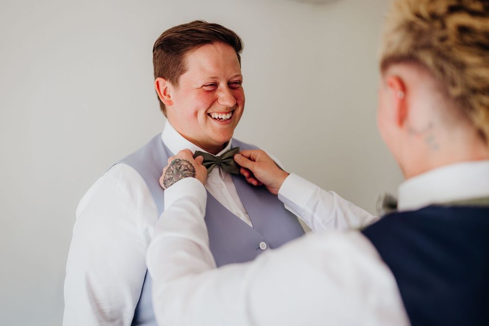 Wedding preparation moment showing adjusting of formal attire in natural light.