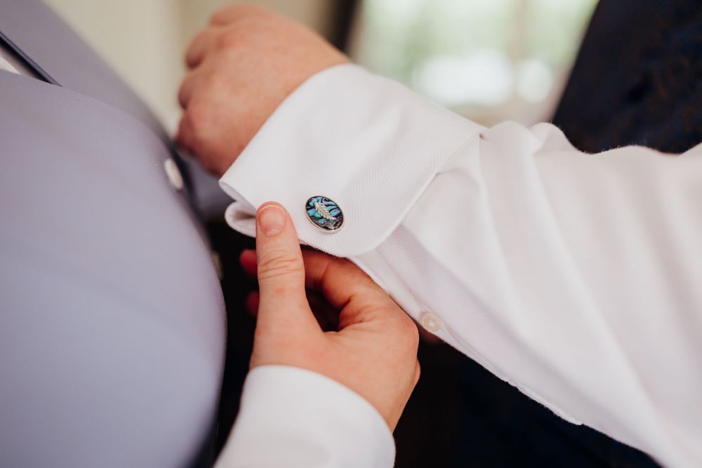 Close-up of hands adjusting a white dress button or fastener.
