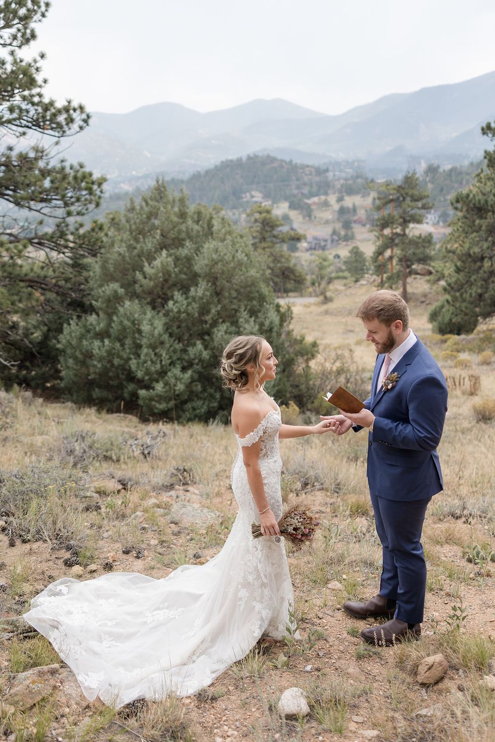 A couple dances together on a mountainside in Colorado, with the bride's white dress flowing gracefully in the wind.